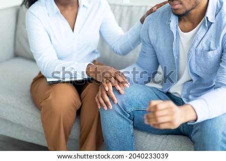 Support for people with mental problems. Psychologist helping depressed young man, touching his hand at office, closeup. Psychotherapy of emotional disorders, PTSD, anxiety