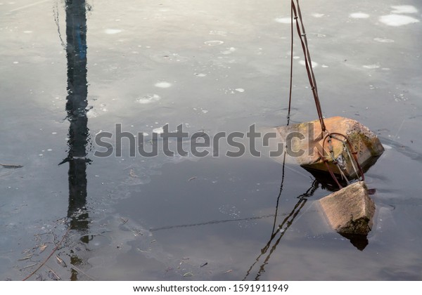Support structure frozen in ice. Steel wire\
ropes supporting pillar in frozen\
water.