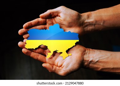 Support for Ukraine in the war with Russia. Hands holding the flag of Ukraine in the shape of the borders of Ukraine. - Shutterstock ID 2129047880