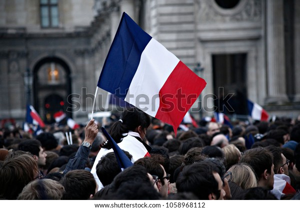 Supporters of\
French presidential election candidate Emmanuel Macron wave French\
national flags as they celebrate in front of the Pyramid at the\
Louvre Museum in Paris on May 7,\
2017.