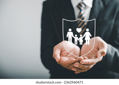 Supporting family futures, Businessman protective gesture complements young family silhouette. Health and house insurance icons symbolize protection, reinforcing family life insurance.