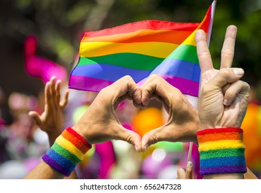 Supporting Hands Make Peace And Heart Signs In Front Of A Rainbow Flag Flying On The Sidelines Of A Summer Gay Pride Parade