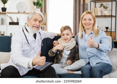 Supportive Attentive Male Doctor Visits Sick Boy Patient At Home Sitting With Mom, Listens To His Complaints And Looking At Camera Showing Thumb Up. Doctor Consulting Preschool Child At Home.