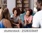 Supportive diverse friends smiling and listening to each other at group therapy session. Therapy, mental health, friendship and support, unaltered.