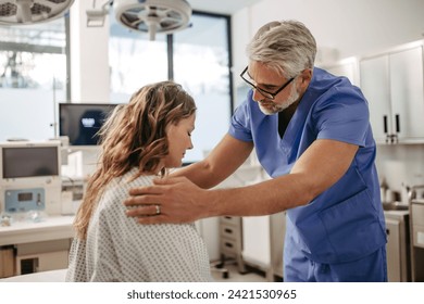 Supportive doctor soothing a worried patient, discussing test result in emergency room. Compassionate physician supporting stressed patient. - Powered by Shutterstock