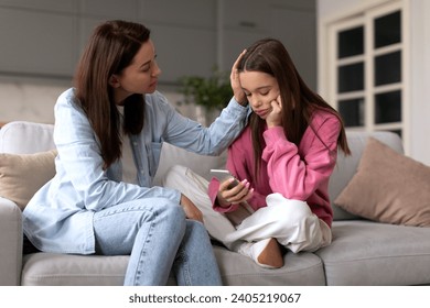 Supportive mother comforting sad teen girl rejected by friends, helping depressed daughter to deal with breakup, child looking at phone - Powered by Shutterstock