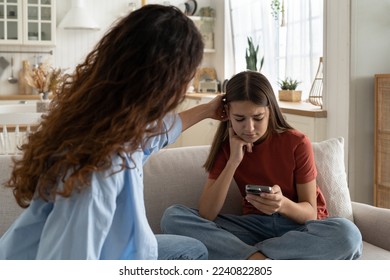 Supportive mother comforting sad teenage girl rejected by friends, helping depressed teen daughter to deal with breakup. Upset depressed adolescent child looking at phone at home, waiting for call