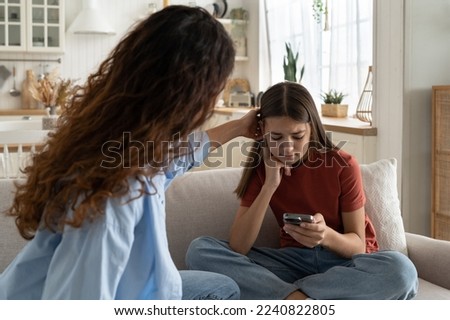 Supportive mother comforting sad teenage girl rejected by friends, helping depressed teen daughter to deal with breakup. Upset depressed adolescent child looking at phone at home, waiting for call