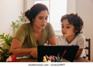 Supportive mother watching an online tutorial with her son. Mother and son going through educational content on a digital tablet. Loving single mother home schooling her young son. - Powered by Shutterstock