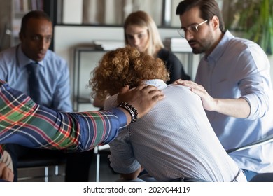 Supportive multiracial employees comfort caress unhappy upset female colleague coworker at team meeting. Caring loving diverse multiethnic people support distressed woman at group gathering.