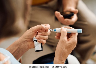 A supportive wife assists her husband as he prepares his diabetes medication at home. - Powered by Shutterstock