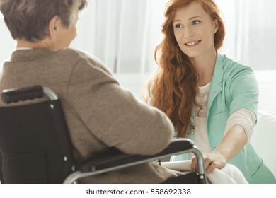 Supportive young nurse looking at elder woman