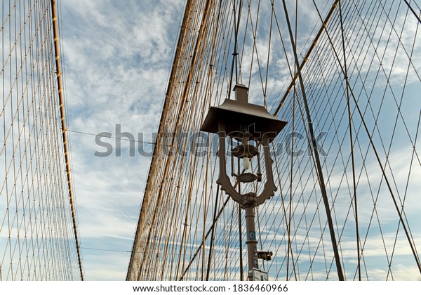 Supports of the Brooklyn Bridge. Geometry of the\
lines of support ropes and a vintage lantern against the sky. New\
York, USA.\
