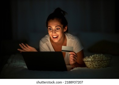 Suprised Woman Lying On Her Bed With Credit Card,using Laptop.