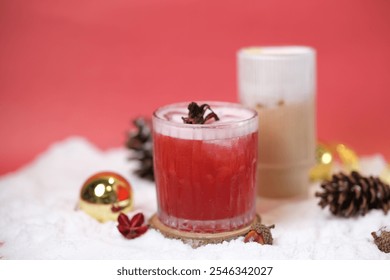 Surabaya, 17 November 2024. red mocktail garnished with dried hibiscus and a creamy latte in the background. Surrounded by ornaments and pinecones, perfect for Christmas gatherings.  - Powered by Shutterstock