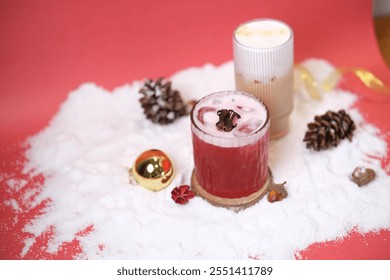 Surabaya, 17 November 2024. red mocktail garnished with dried hibiscus and a creamy latte in the background. Surrounded by ornaments and pinecones, perfect for Christmas gatherings. - Powered by Shutterstock