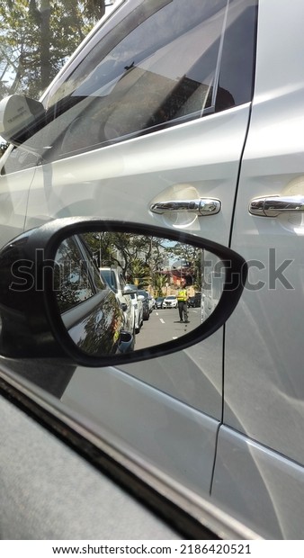 Surabaya, East Java,Indonesia-August 3 2022:  Car\
rearview mirror or side mirror to see the side of the vehicle.\
driving in the city, trafic\
jam.