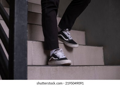 Surabaya, Indonesia - 2 August 2022: The Feet Of A Man Walking Down The Stairs Wearing Sneakers