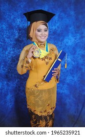 Surabaya, Indonesia; closed up graduation wearing a golden yellow kebaya dress while holding a graduation medal with a blue background at the Faculty of Medicine UNAIR on February 11, 2014