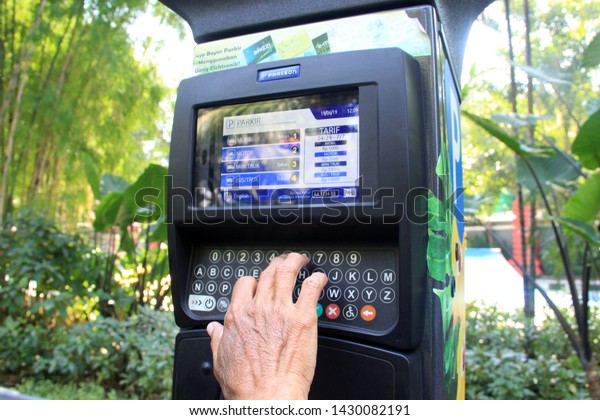 surabaya -\
indonesia. June 19 2019. A man makes a parking payment through an\
electronic meter parking engine. the facility is a technological\
advance in the field of\
transportation