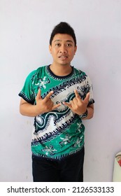 Surabaya, Indonesia, March 12 2011:  a man posing wearing a t-shirt with a Javanese batik pattern in green and white in front of a white wall