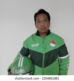 SURABAYA , INDONESIA - SEPTEMBER 05, 2022: : A Grab Driver Is Ready With His Full Attributes, Namely Jackets And Helmets.