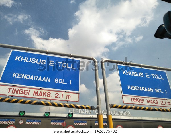 Surabaya, Indonesia - Translation in english:\
khusus special e toll vehicle volume 1, height maximum 2.1 m.  Blue\
white sign board isolate on sky blue white clouds background with\
distraction element.
