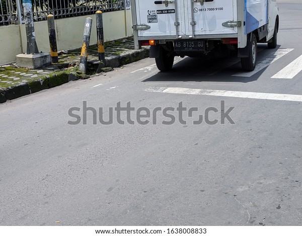 Surakarta, Indonesia - February 7 2020: White\
Cargo Truck Passing on the Zebra Crossing Sign at Surakarta,\
Central Java, Indonesia in the\
Afternoon