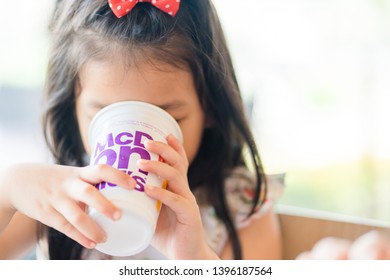 Suratthani, Thailand, May 11, 2019: McDonald's Soft Drink. Little Asian Girl Drinking Coke Coca Cola Drink In McDonald's Restaurant.