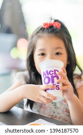 Suratthani, Thailand, May 11, 2019: McDonald's Soft Drink. Little Asian Girl Drinking Coke Coca Cola Drink In McDonald's Restaurant.