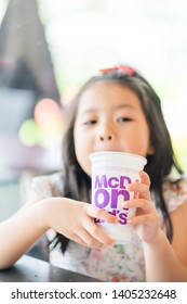 Suratthani, Thailand, May 11, 2019: McDonald's Soft Drink. Little Asian Girl Drinking Coke Coca Cola Drink In McDonald's Restaurant.