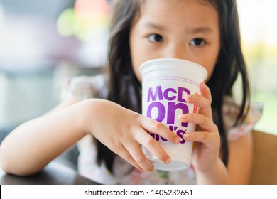 Suratthani, Thailand, May 11, 2019: McDonald's Soft Drink. Little Asian Girl Drinking Coke Coca Cola Drink In McDonald's Restaurant.