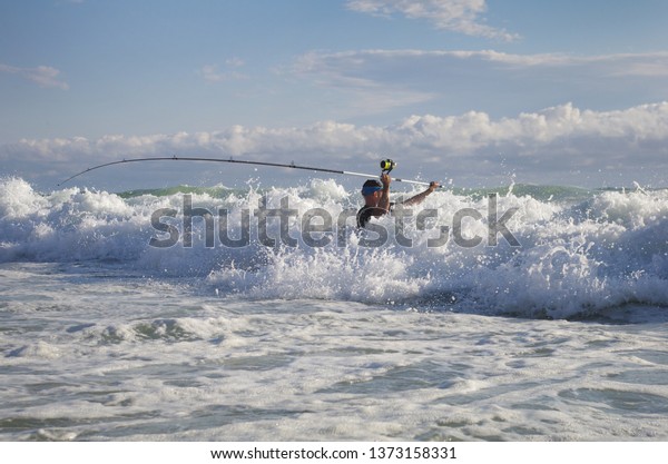 Surf fisherman\
in the waves. Surf fishing\
scene