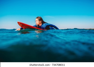 Surf girl floats on surfboard. Woman in ocean during surfing. Surfer and ocean