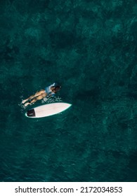 Surf girl swim with surfboard in transparent ocean. Aerial view