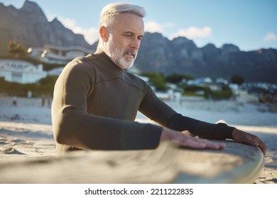 Surf, sand and sports with a man on the beach for surfing, training or exercise on a summer day. Fitness, workout and travel with a mature surfer cleaning a surfboard while on retirement vacation - Powered by Shutterstock