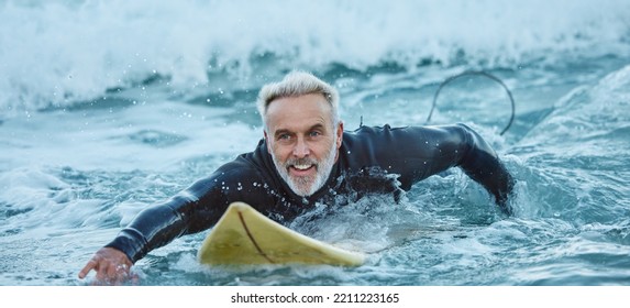 Surf, sea and sports with a mature man surfer in the water for sport, fitness and surfing during summer. Training, workout and exercise with a male athlete on his surfboard in the ocean alone - Powered by Shutterstock