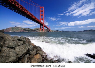 Surf Splashes Over Rocks Under Golden Gate Bridge As Seen From The Fort Point Beach.