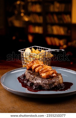 surf and turf close-up with thick slice of sirloin steak and prawns with blackberry pub jam with country fries