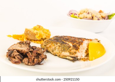 Surf And Turf Dinner - Grilled Wild Salmon On White Plate With Sliced Tenderloin Steak And Twice Baked Potato.  Salad In Background.  Brightly Lit With Copy Space.