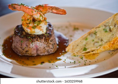 Surf And Turf. Lobster And Steak Entree. Filet Mignon Topped With Chanterelle Mushrooms And Maine Lobster Tail Topped With Drawn Butter Served On White Dinner Plate. Classic Steakhouse Menu Favorite.