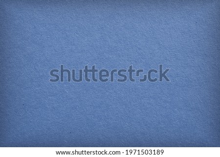 The surface of blue cardboard. Paper texture with cellulose fibers. Elegant tinted background with vignetting. Glamorous generic gray paperboard wallpaper. Beautiful textured backdrop. Top-down. Macro