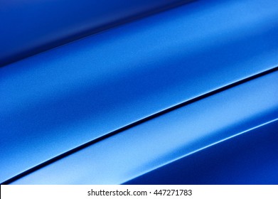 Surface of blue sport sedan car metal hood, part of vehicle bodywork, steel gradient line pattern, selective focus 