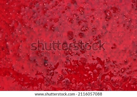Surface of dessert from dark-red sweet raspberry jam fixed with a close-up photo shooting. View from above.          