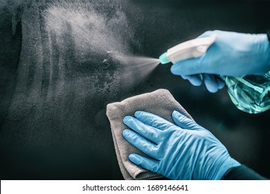 Surface home cleaning spraying antibacterial sanitizing spray bottle disinfecting against COVID-19 spreading wearing medical blue gloves. Sanitize surfaces prevention in hospitals and public spaces.