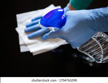 surface home cleaning spraying antibacterial sanitizing spray bottle disinfecting against COVID-19 spreading wearing medical blue gloves. Sanitize surfaces prevention in hospitals and public spaces. - Shutterstock ID 1704761098