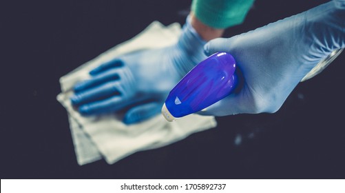 pulizia della casa di superficie spruzzatura flacone spray igienizzante antibatterico disinfettante contro la diffusione di COVID-19 indossando guanti blu medici. Sanificare la prevenzione delle superfici negli ospedali e negli spazi pubblici.