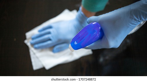 surface home cleaning spraying antibacterial sanitizing spray bottle disinfecting against COVID-19 spreading wearing medical blue gloves. Sanitize surfaces prevention in hospitals and public spaces. - Shutterstock ID 1707248872