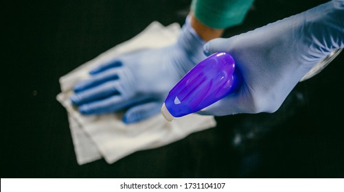 surface home cleaning spraying antibacterial sanitizing spray bottle disinfecting against COVID-19 spreading wearing medical blue gloves. Sanitize surfaces prevention in hospitals and public spaces. - Shutterstock ID 1731104107