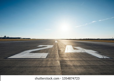 Surface level of airport runway with road marking and number 24 against clear sky. - Shutterstock ID 1354874723